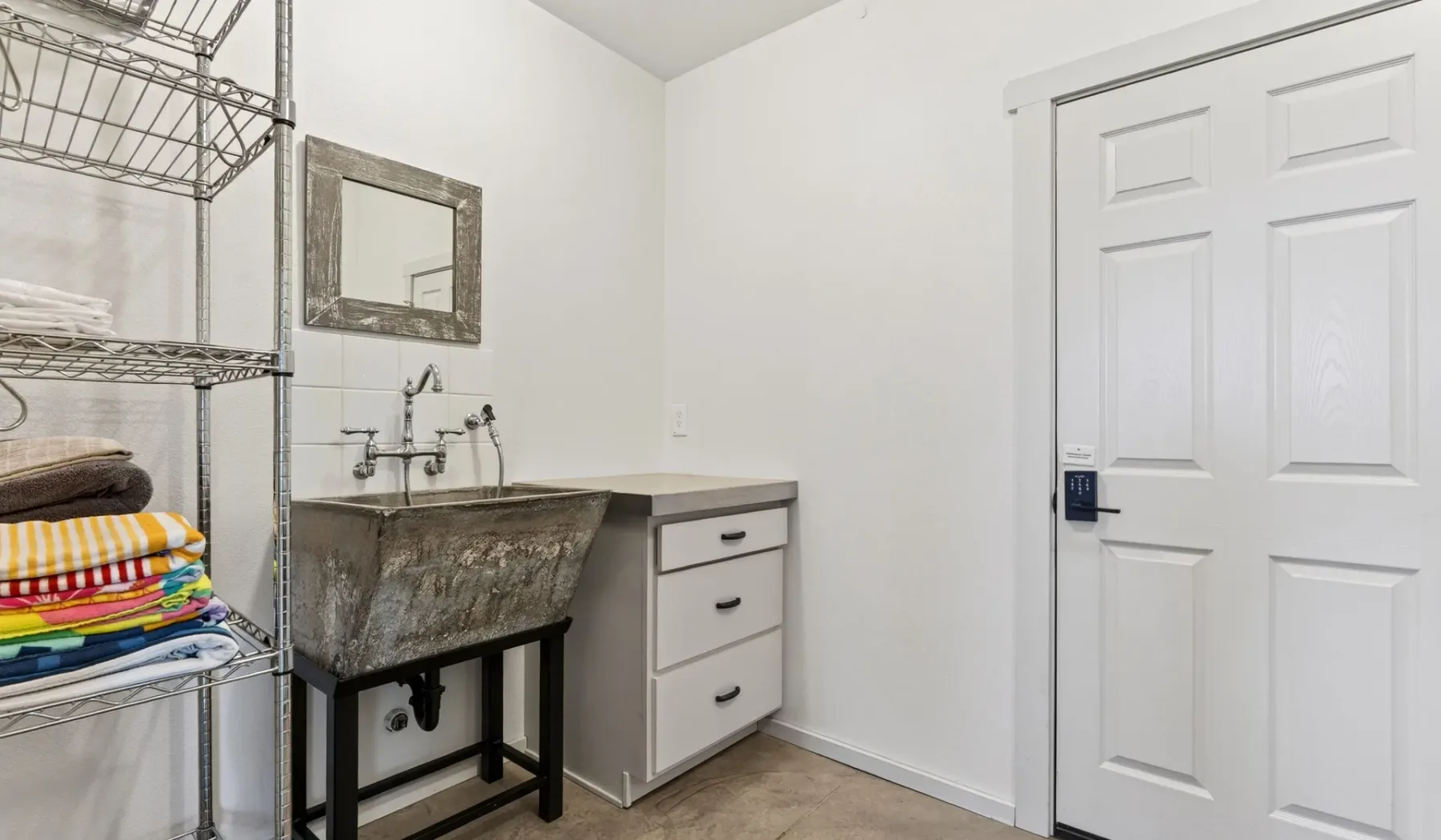 Un baño con un lavabo grande, un espejo y una puerta blanca con paneles.