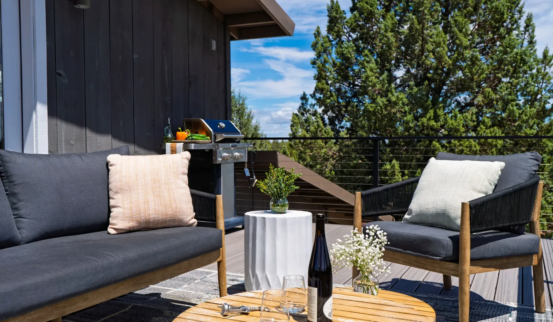 Una zona de estar en una terraza exterior con asientos acolchados y una mesa pequeña.