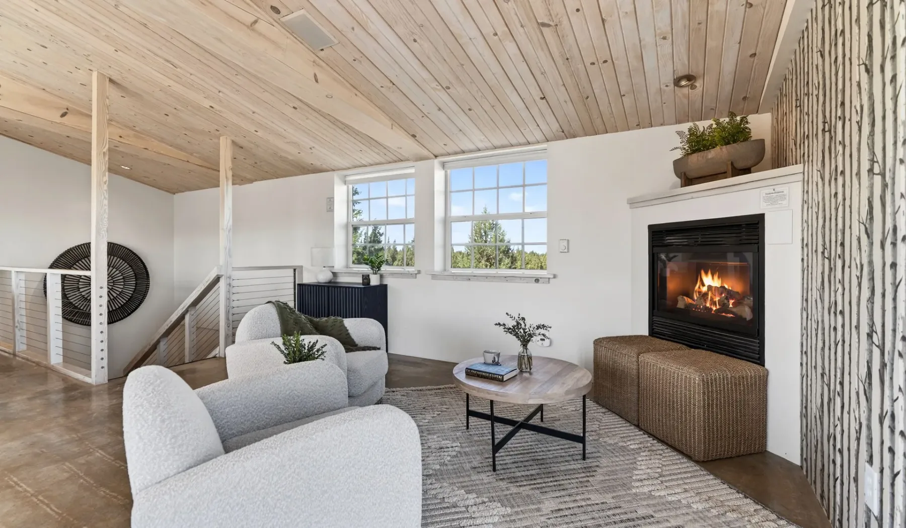 Una sala luminosa con asientos, ventanas grandes y una chimenea encendida.