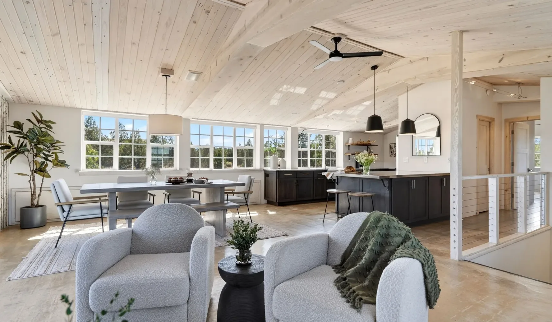 Una luminosa sala-comedor de planta abierta con una isla de cocina y grandes ventanas.