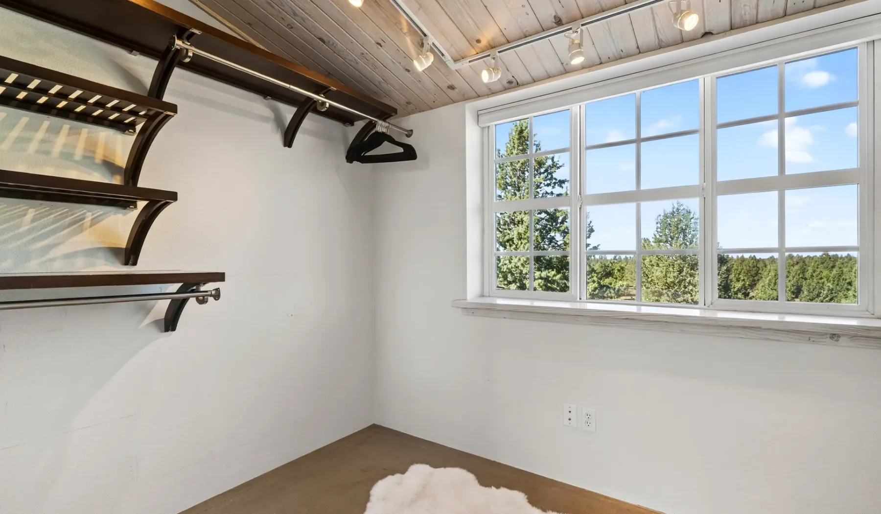 Una habitación luminosa con estantes de pared y una ventana grande.