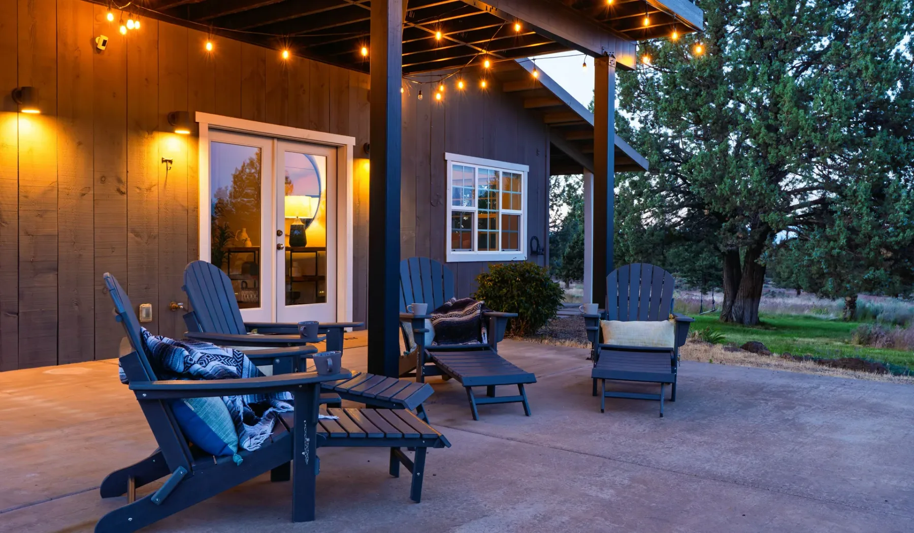 Un patio al aire libre con asientos bajo un techo adornado con luces.