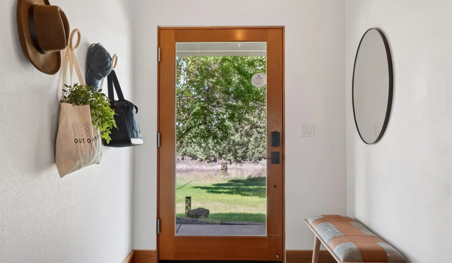 Una entrada con una puerta de madera acristalada y un banco.