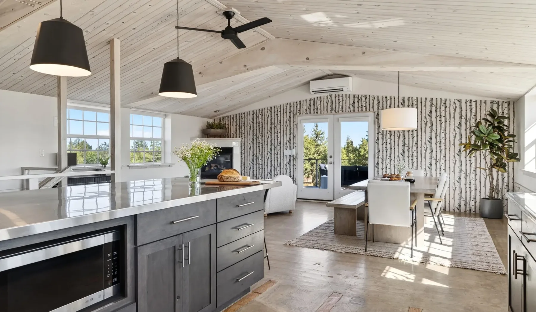 Una luminosa cocina y comedor de concepto abierto, con grandes ventanas y techo abovedado.