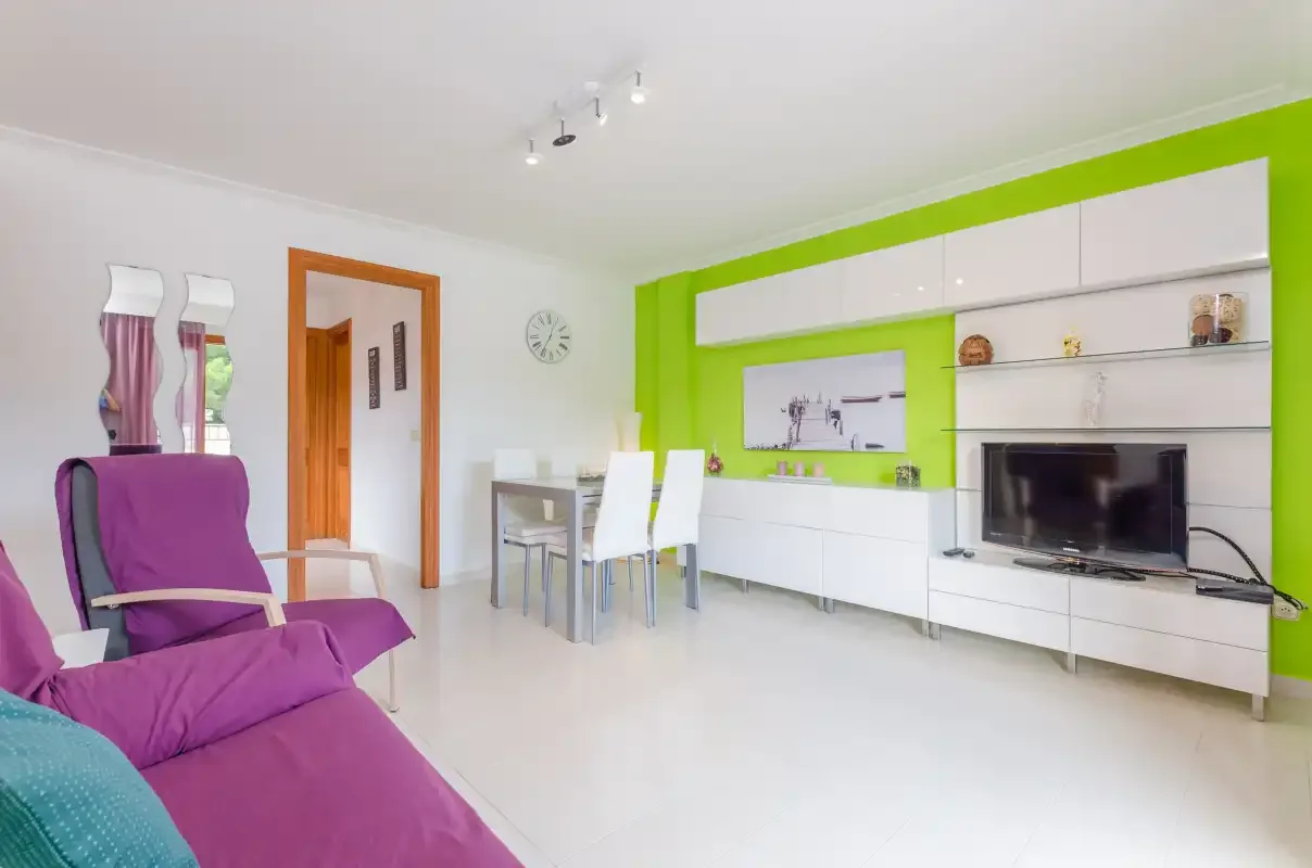 A bright living room with purple seating and a white dining table.