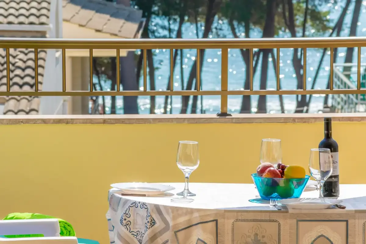 A balcony dining area with a set table overlooking trees and water.