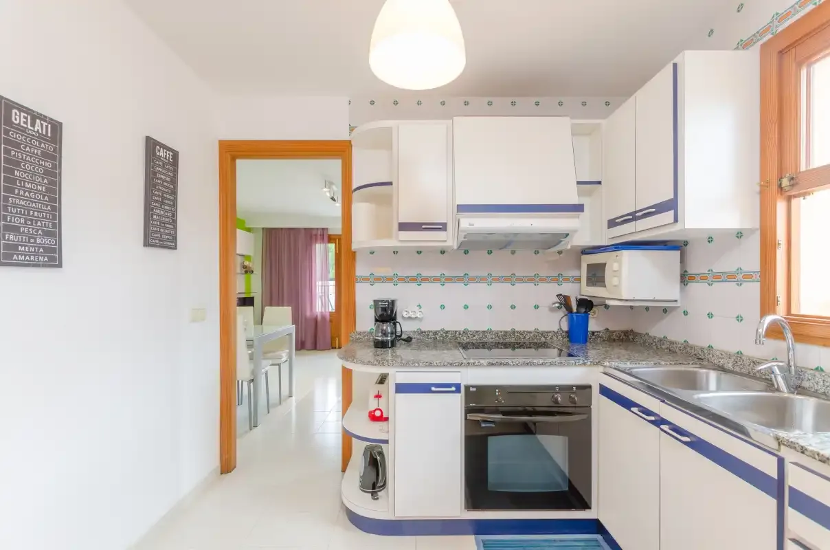 A bright kitchen with white cabinets, a countertop, and an oven.