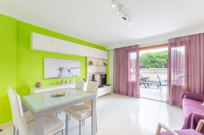 A bright living and dining area with a glass table and sliding doors to a balcony.