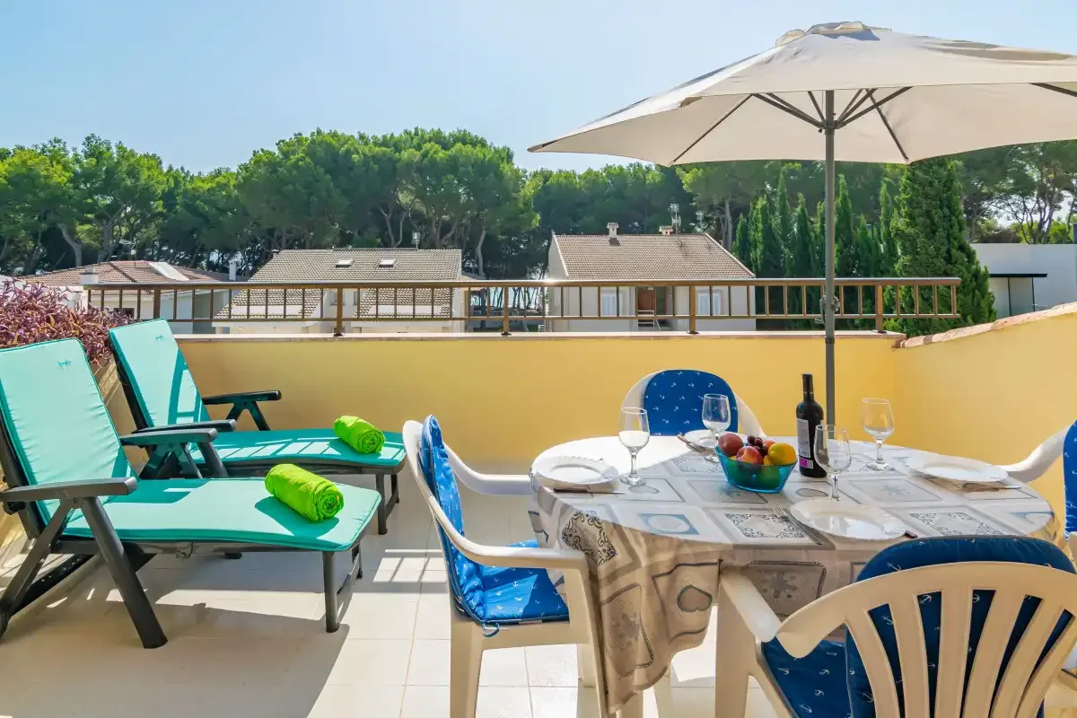 A sunny outdoor dining area with a table, chairs, and a large umbrella.