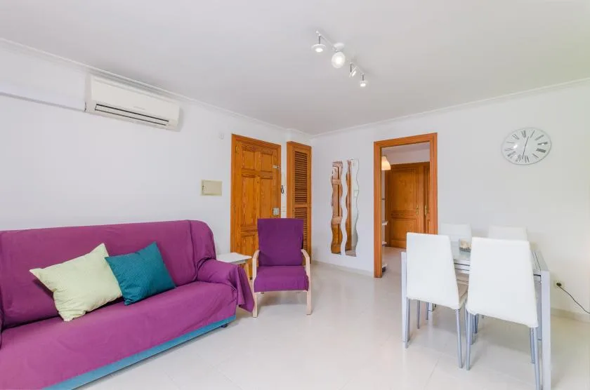 A bright living and dining area with colorful seating and a white table.