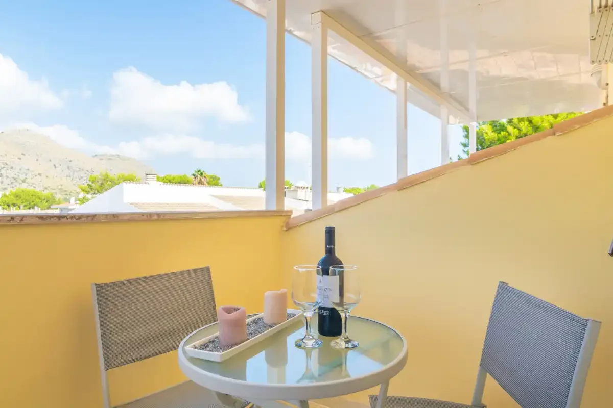A small outdoor dining area with a round glass table and views of the surrounding hills.