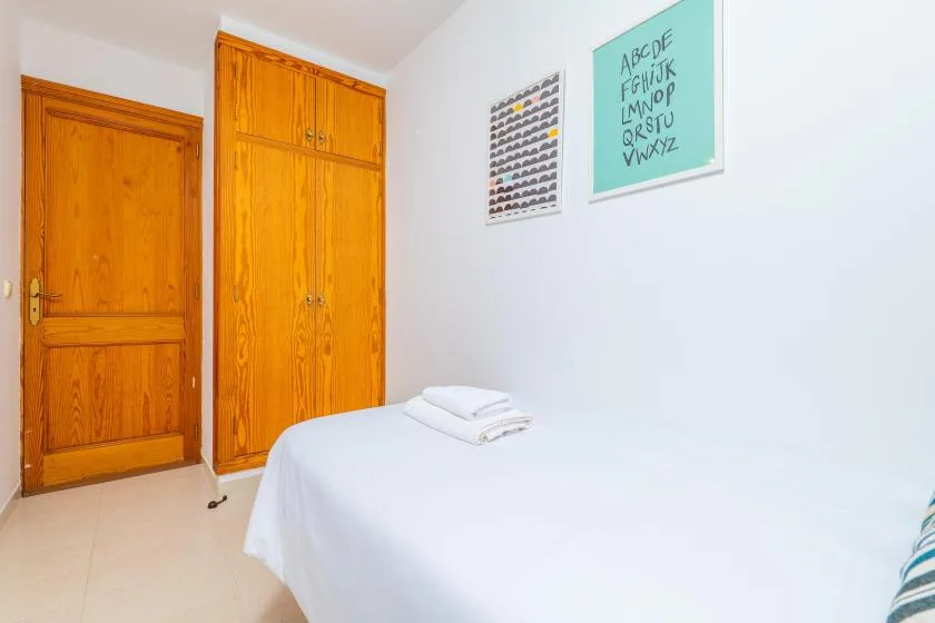 A bedroom with a neatly made bed and wooden storage cabinets.