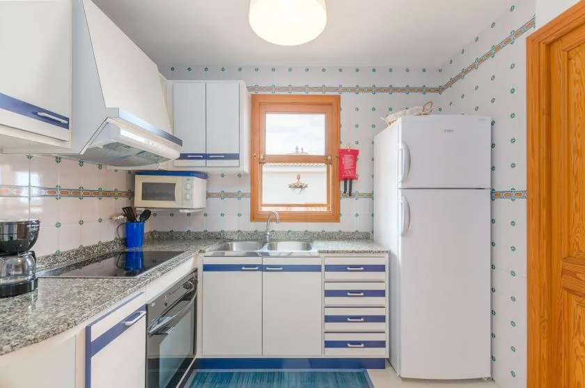 A bright kitchen with blue-and-white cabinets and a patterned tile backsplash.
