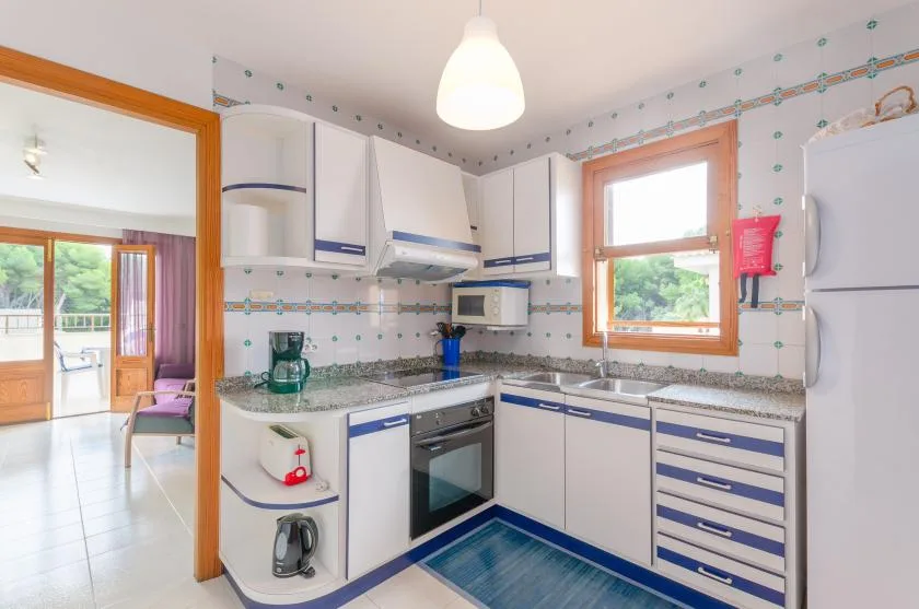A bright kitchen with white cabinets, blue trim, and a countertop.
