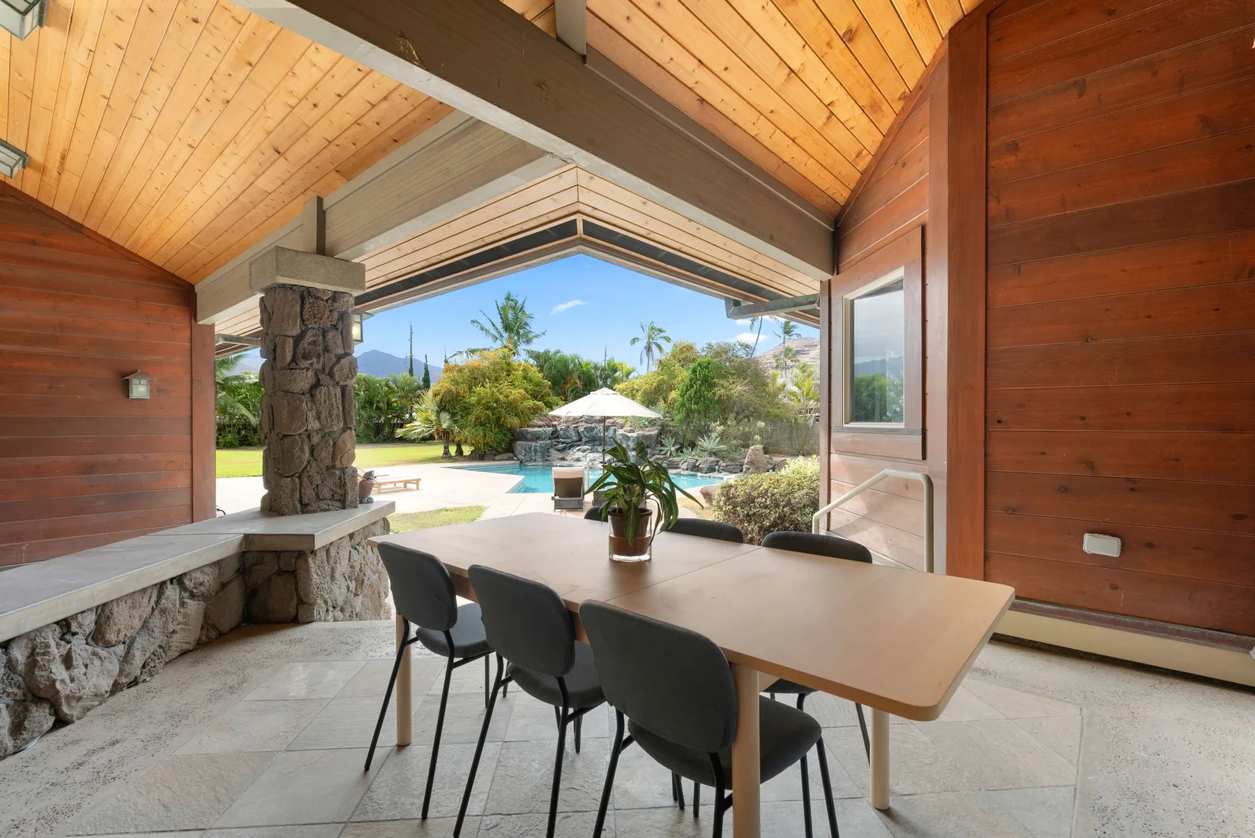 Un comedor cubierto se abre a un patio con piscina y jardín.