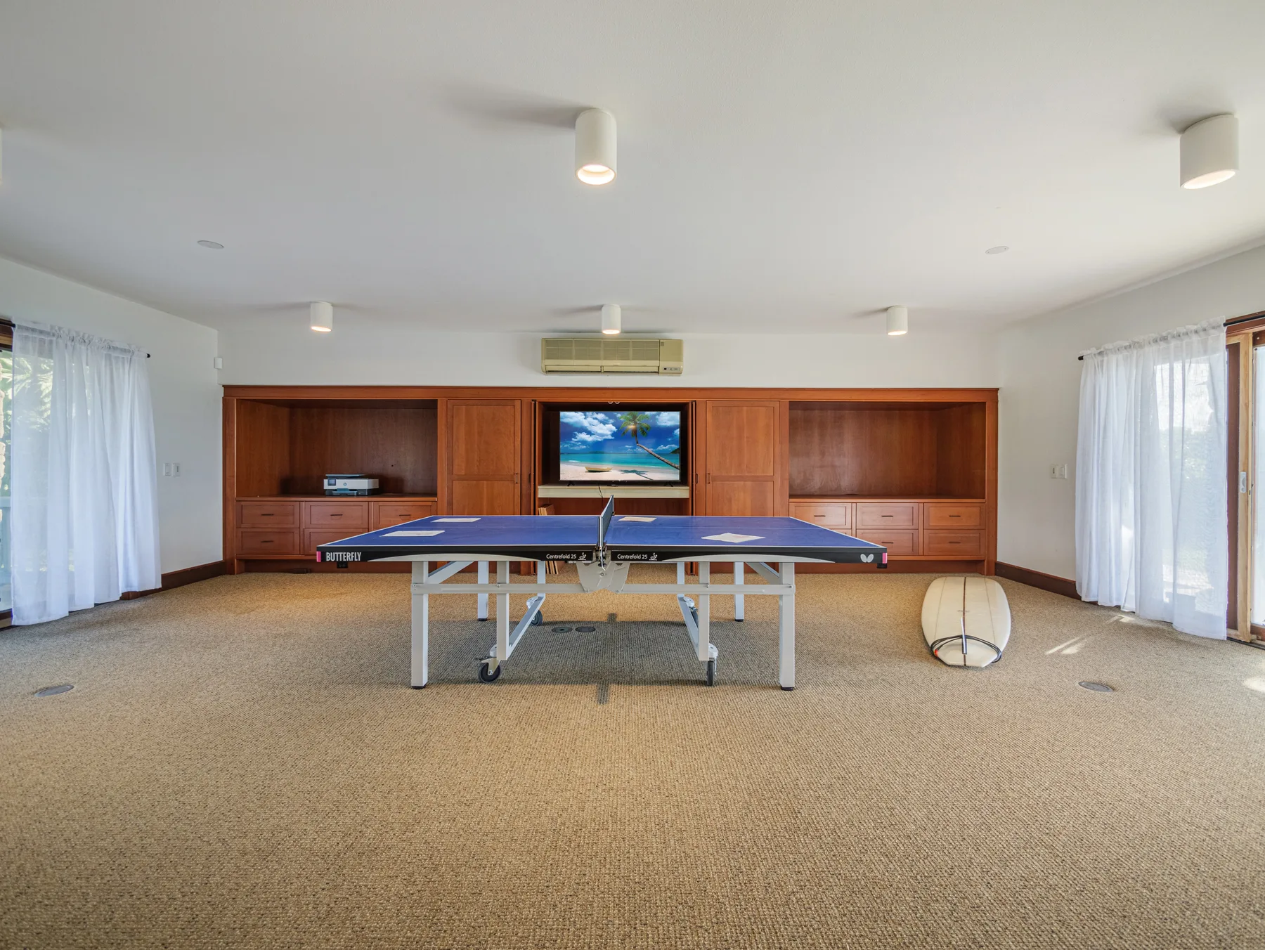 Una amplia sala recreativa con una mesa de ping-pong y una pared revestida de madera.