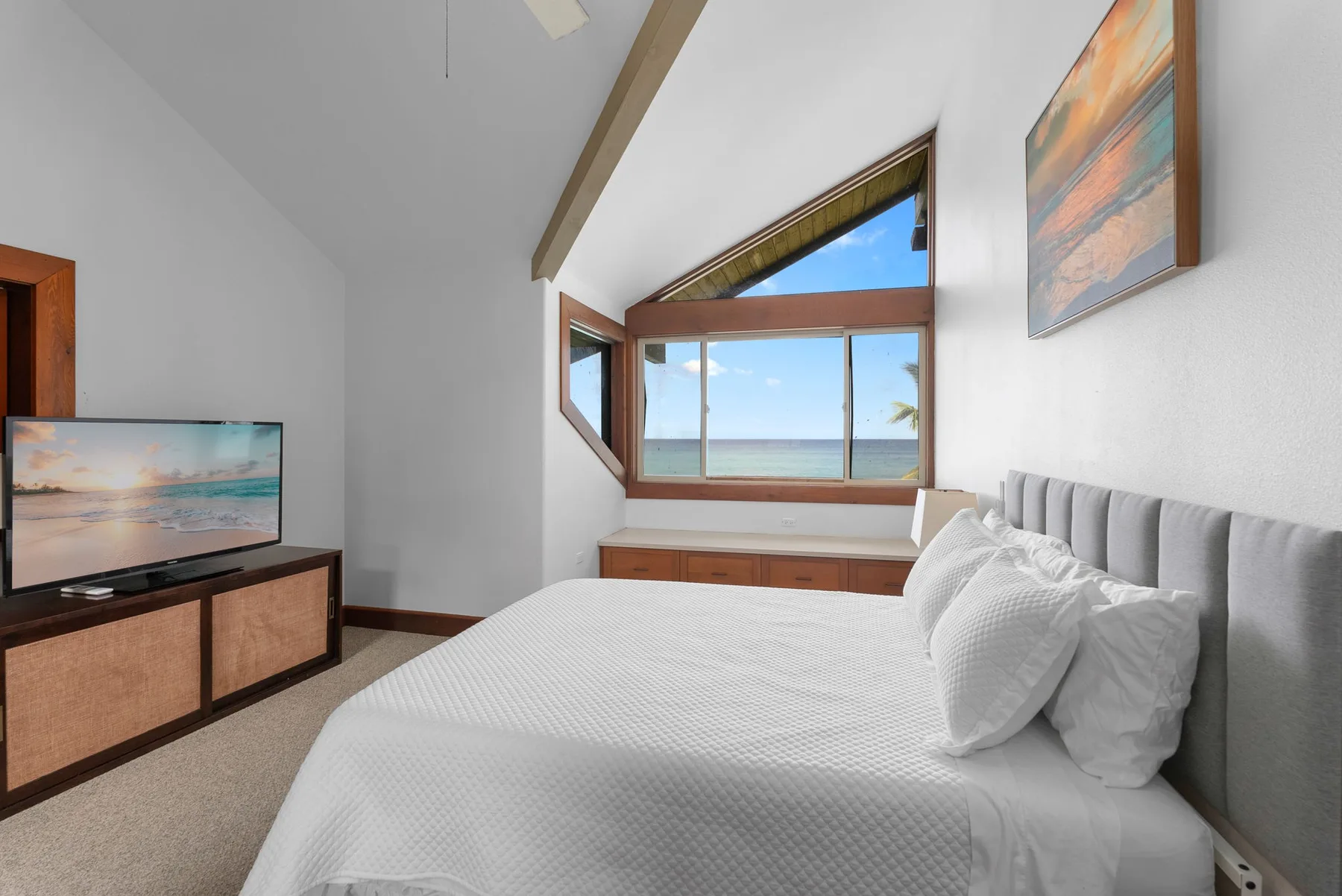 Un dormitorio con cama, televisor y grandes ventanas con vistas al agua.
