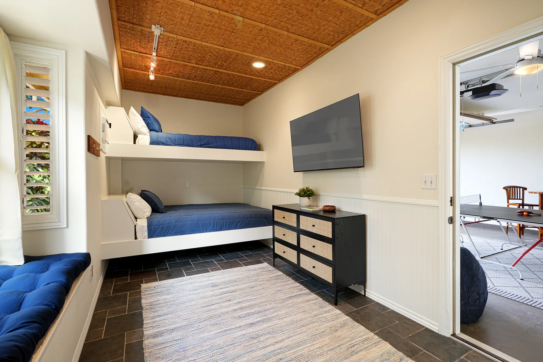 A compact bedroom with two built-in beds, a television, and a dresser.