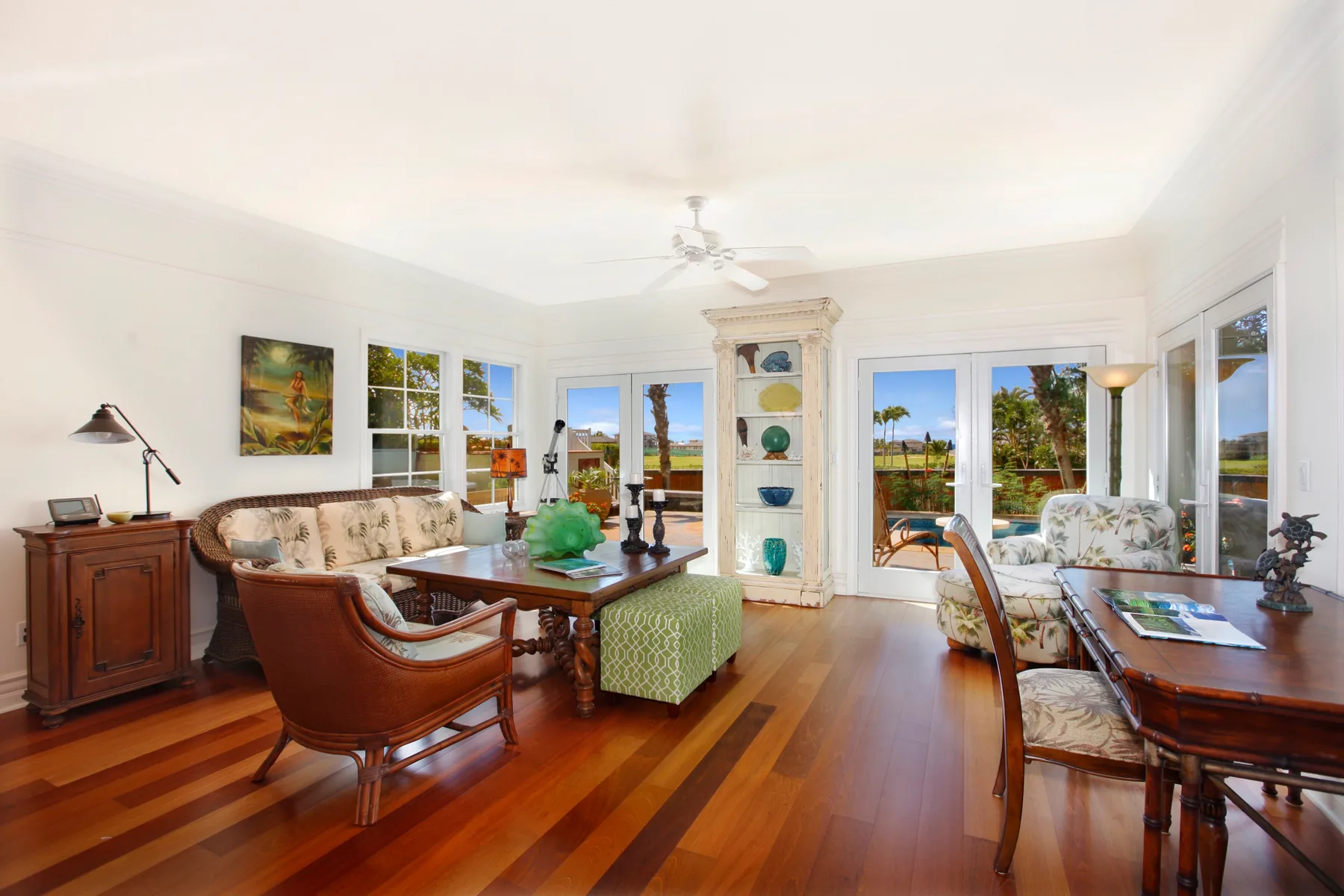 A bright living room with seating, a coffee table, and windows overlooking greenery.
