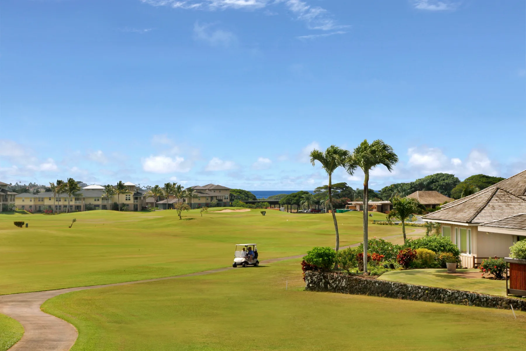 A golf course stretches across a landscaped resort grounds beneath a blue sky.