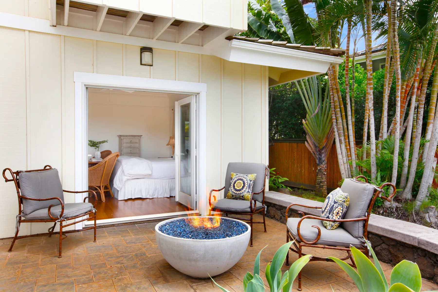 A patio with a round fire feature sits beside an open bedroom.