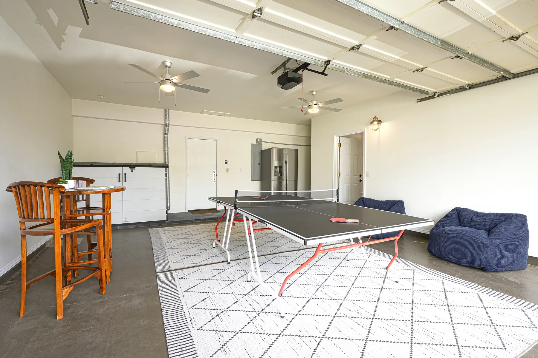 A garage recreation area with a ping-pong table and seating.