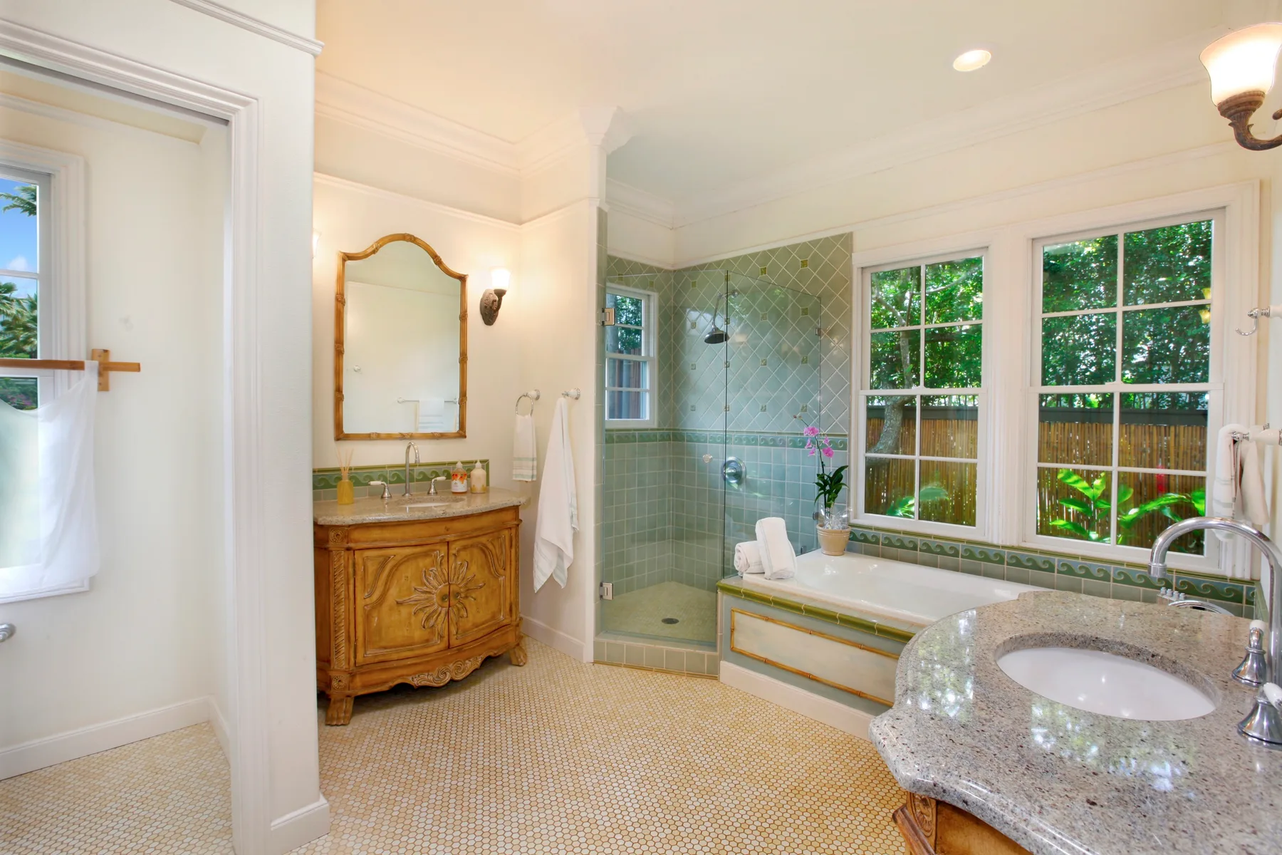 A bright bathroom features a glass-enclosed shower, bathtub, and vanity.