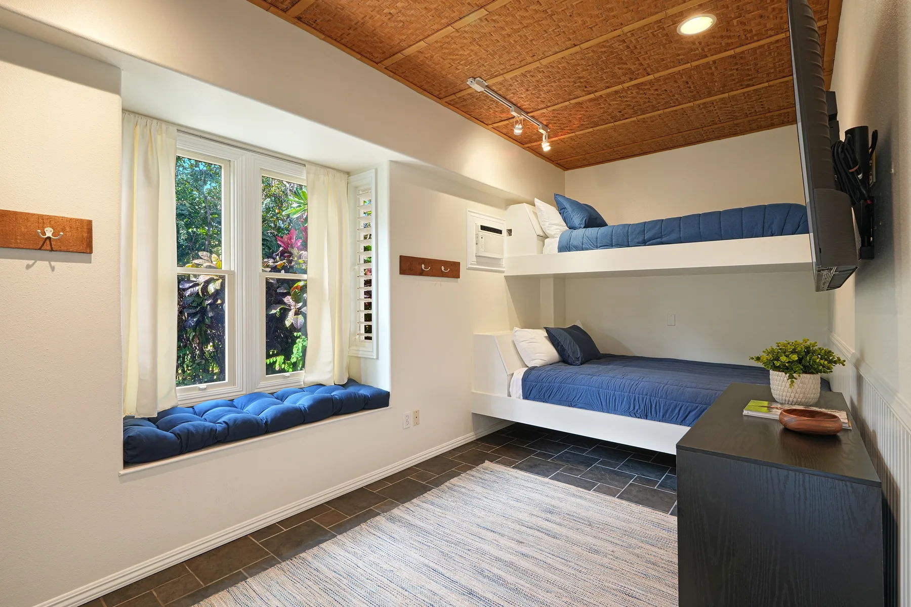 A bedroom with two built-in beds, blue bedding, and a window seat.