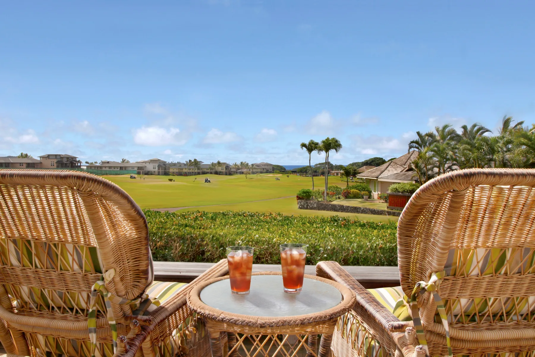 A balcony seating area overlooks a green golf course under a blue sky.