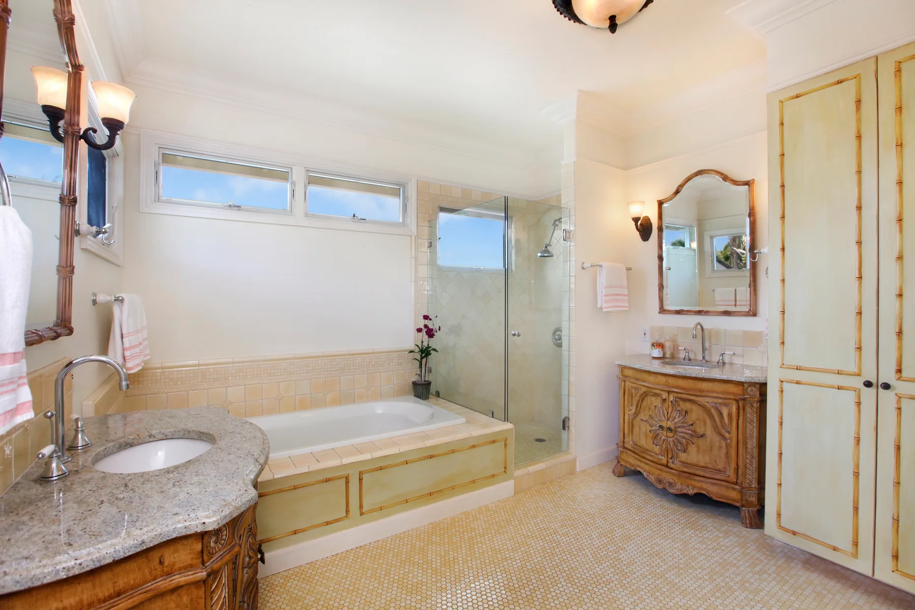 A bright bathroom with a bathtub, glass shower, and vanity.