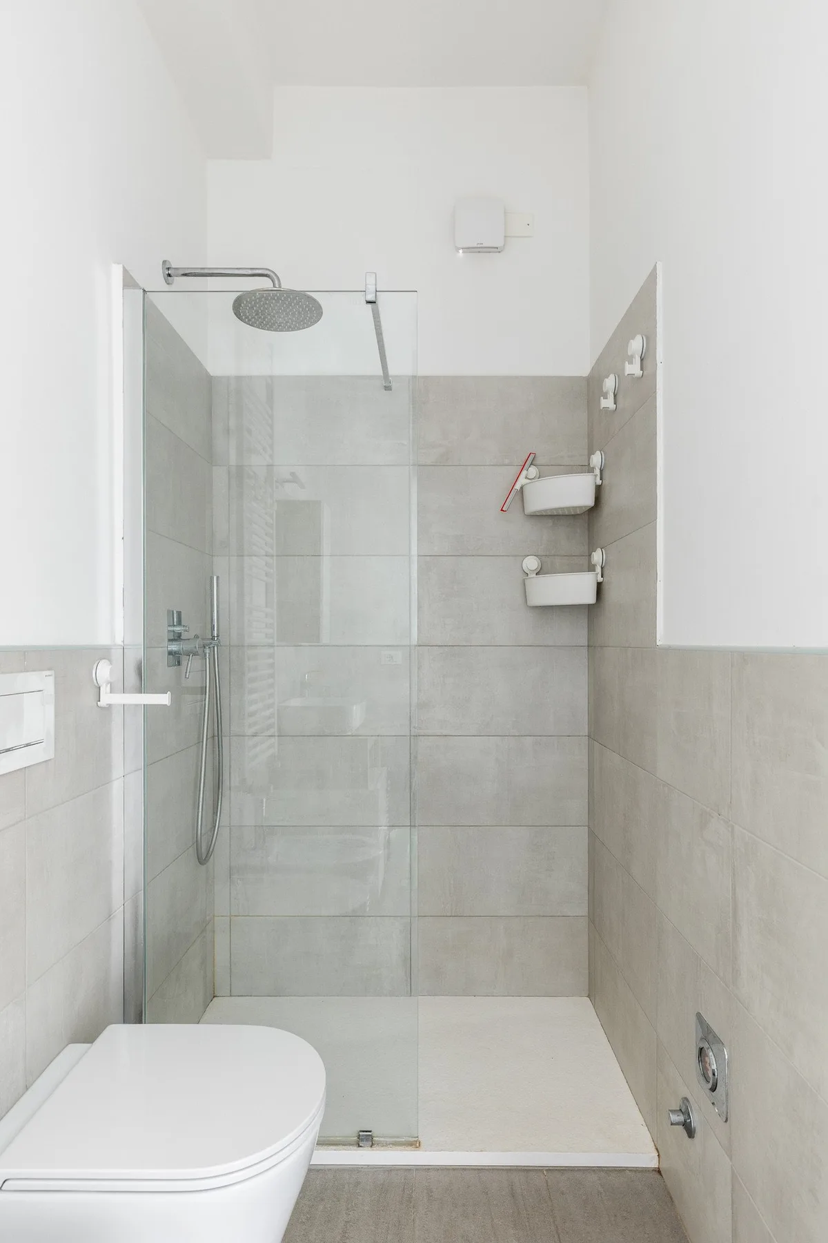 Un baño luminoso con una ducha de vidrio y accesorios de pared.