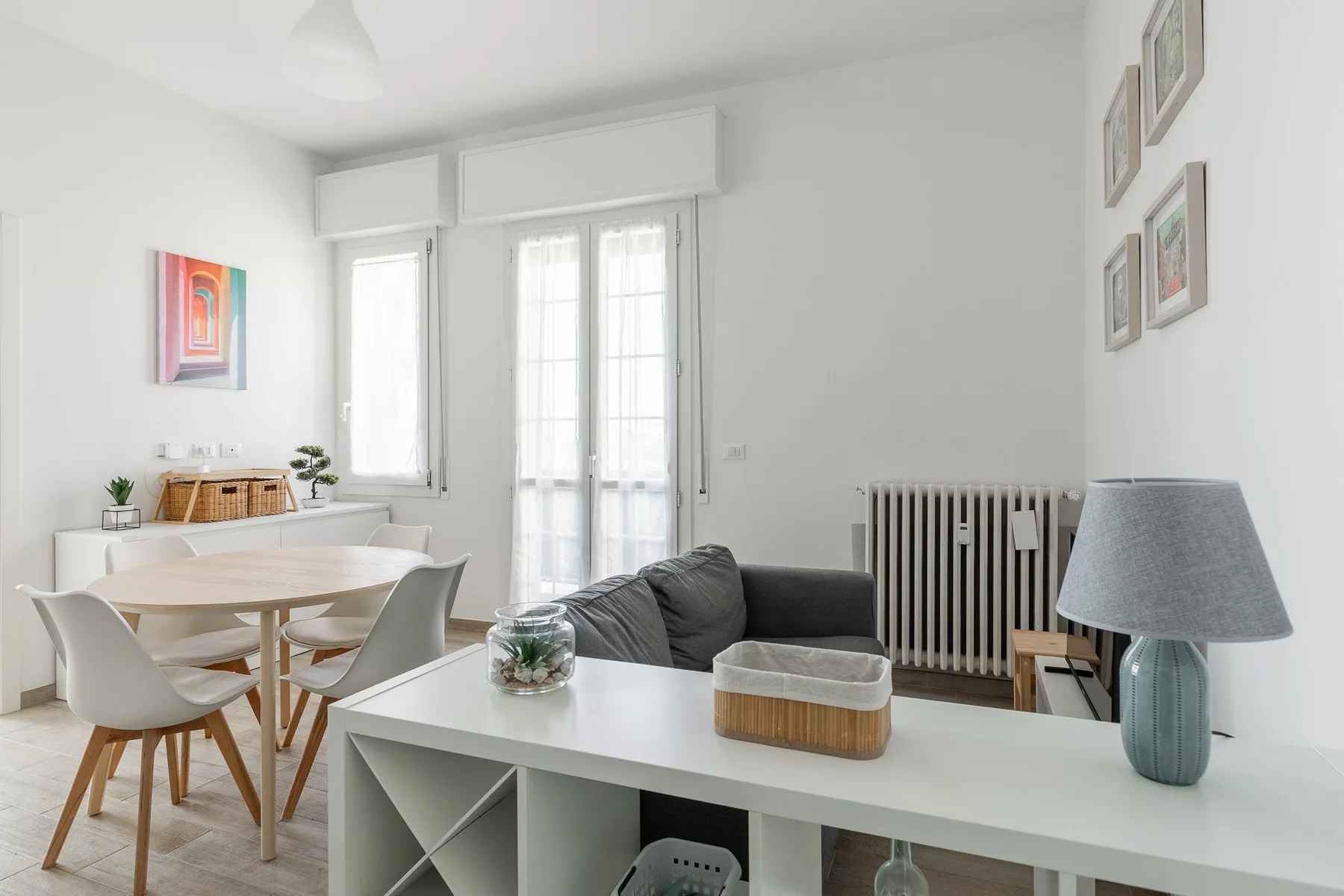 Una luminosa sala de estar y comedor con mesa, asientos y ventanas altas.