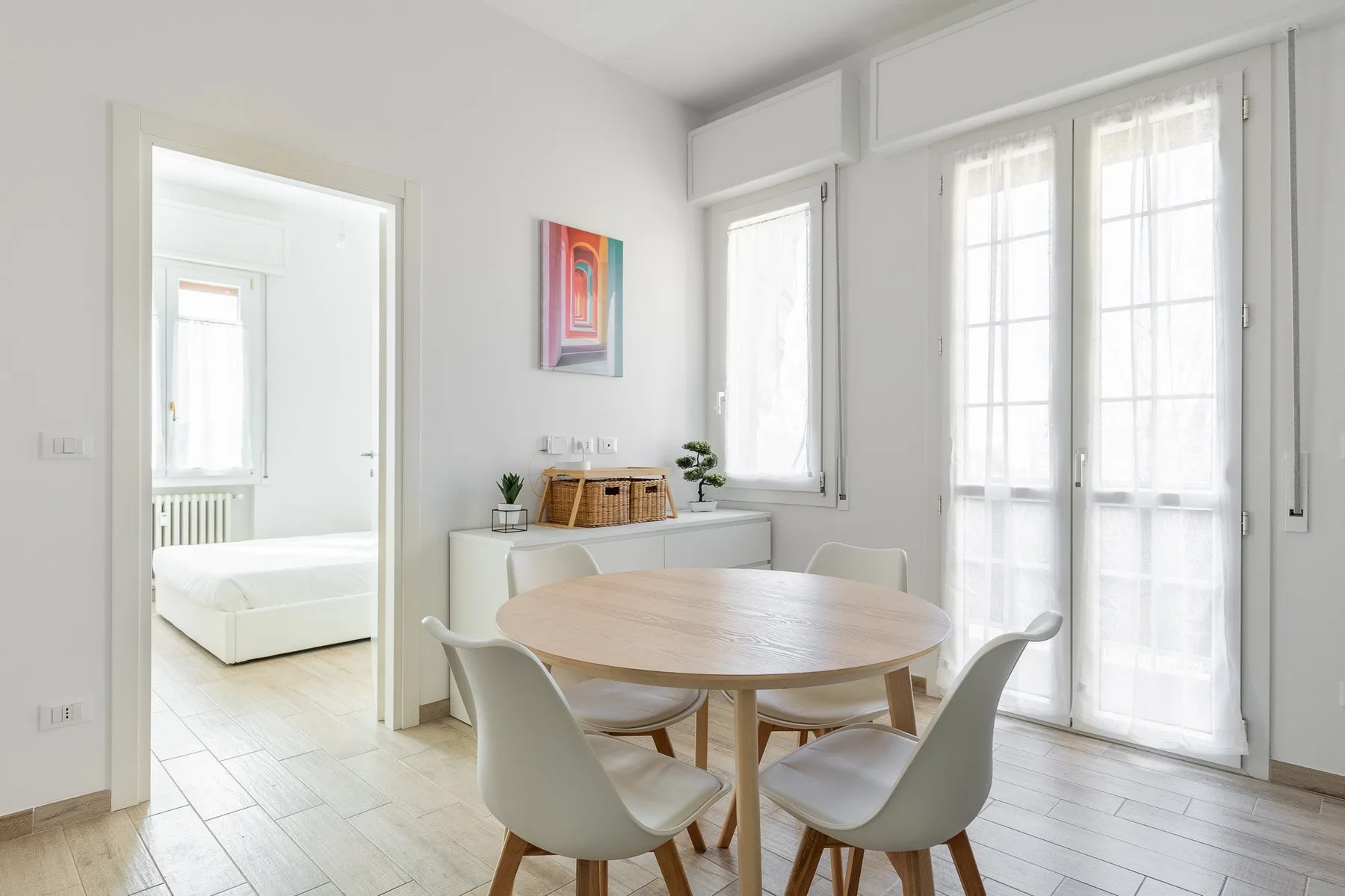 Un comedor luminoso con una mesa redonda de madera y grandes ventanas.