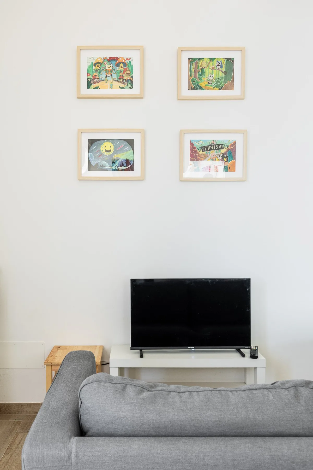 Una sala de estar con un televisor sobre un mueble y asientos grises.