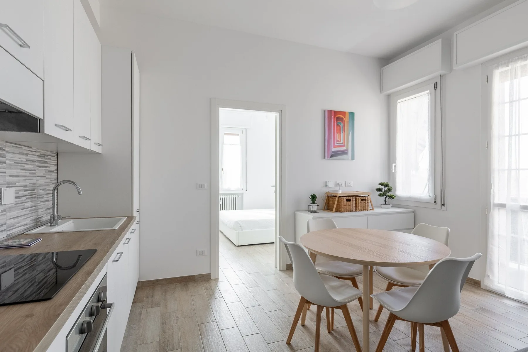 Un luminoso comedor y cocina se conectan con un dormitorio a través de una puerta.