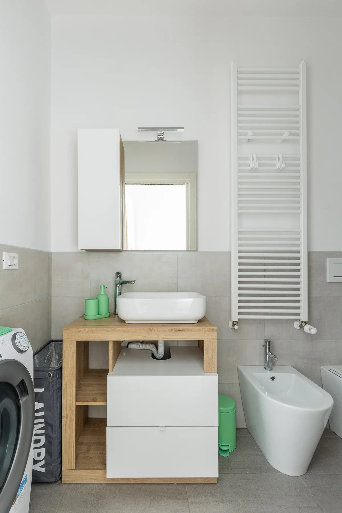 Un baño con lavabo, espejo, toallero calefactor de pared y bidé.