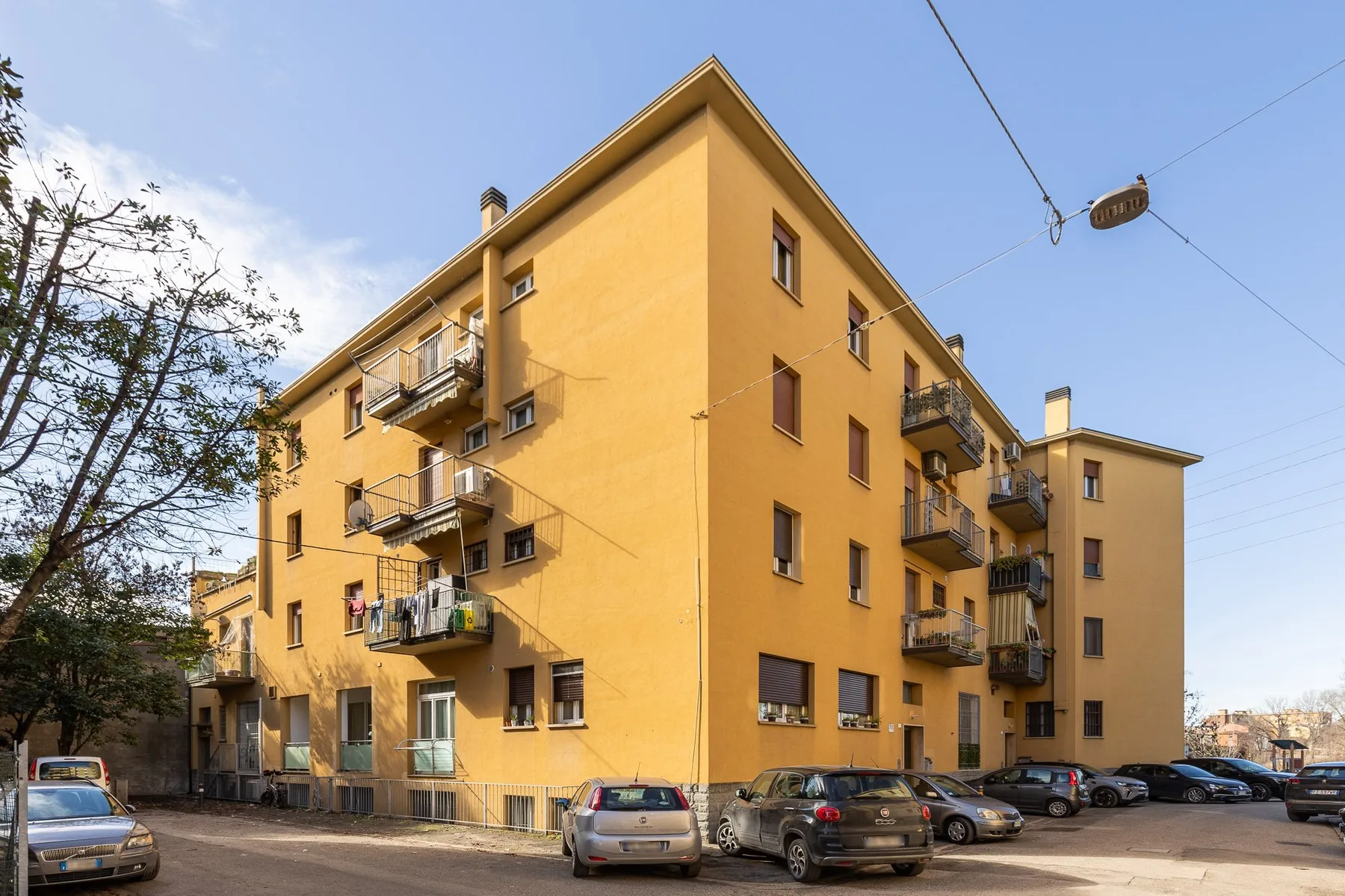 Un edificio de apartamentos amarillo de varias plantas con balcones da a una calle.