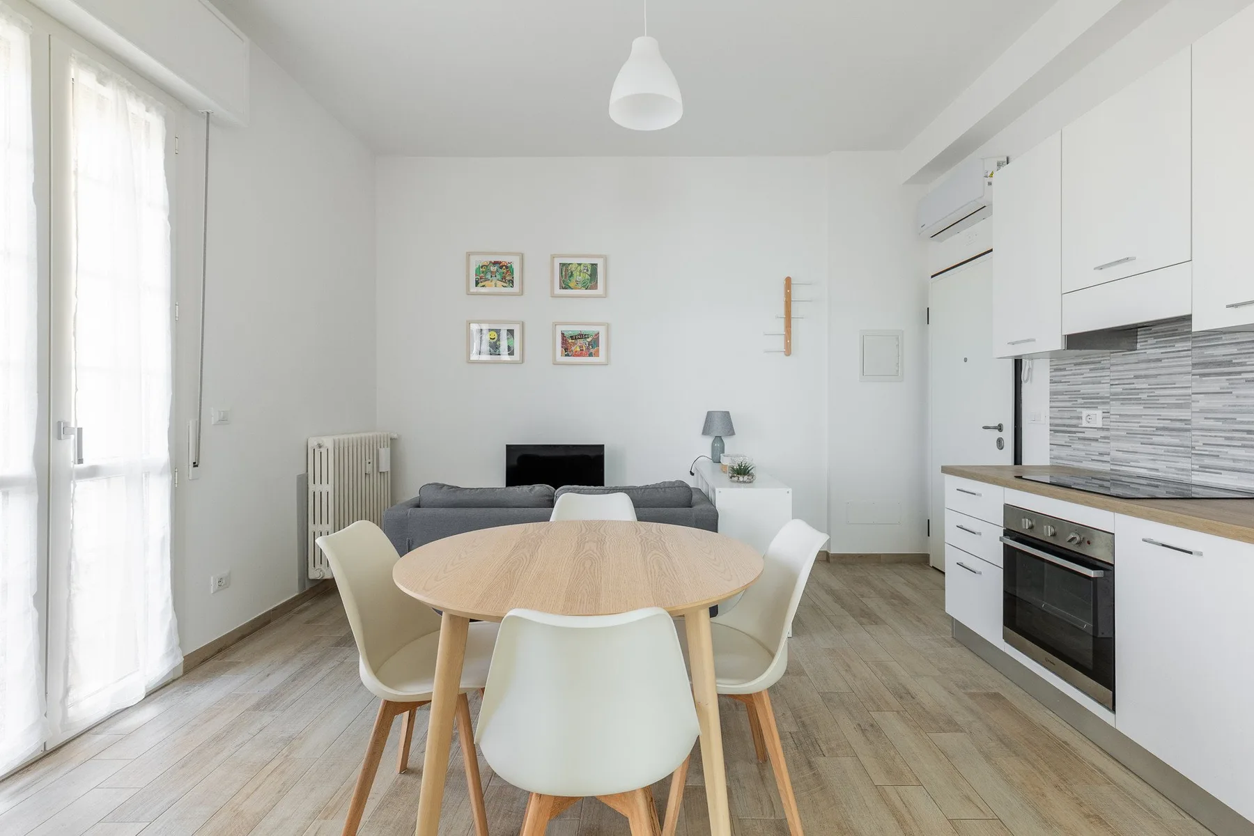 Una luminosa sala de estar y comedor con una mesa redonda y cocina.