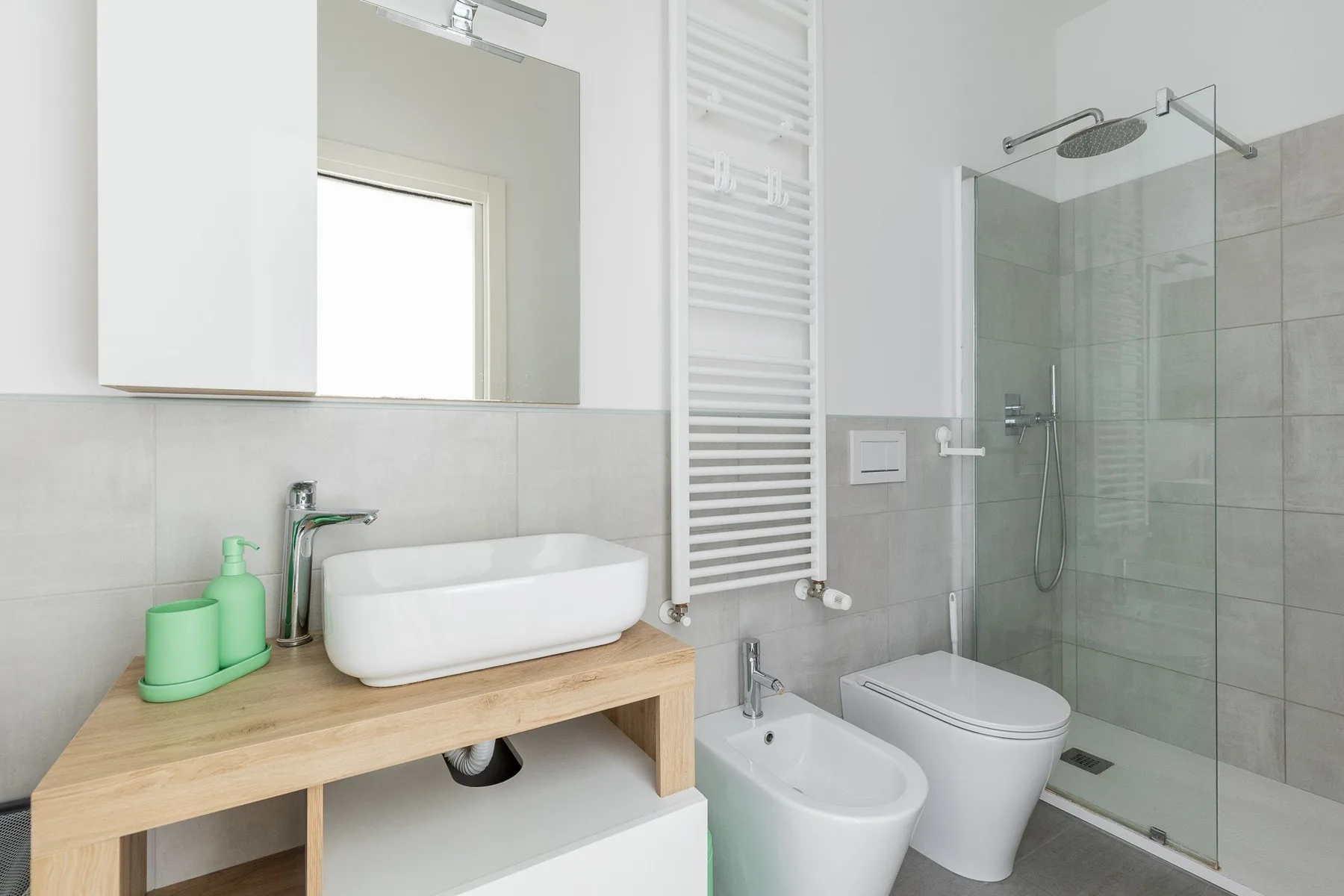 Un baño luminoso con lavabo, inodoro y ducha de vidrio.