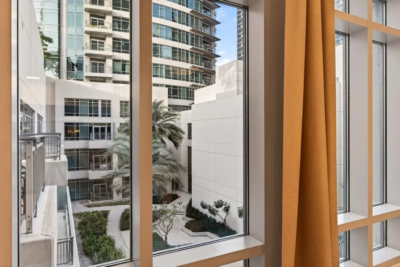 A window overlooks nearby modern buildings and landscaped courtyard areas.