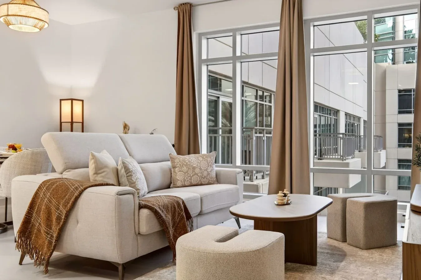 A bright living room with seating, a coffee table, and tall windows.