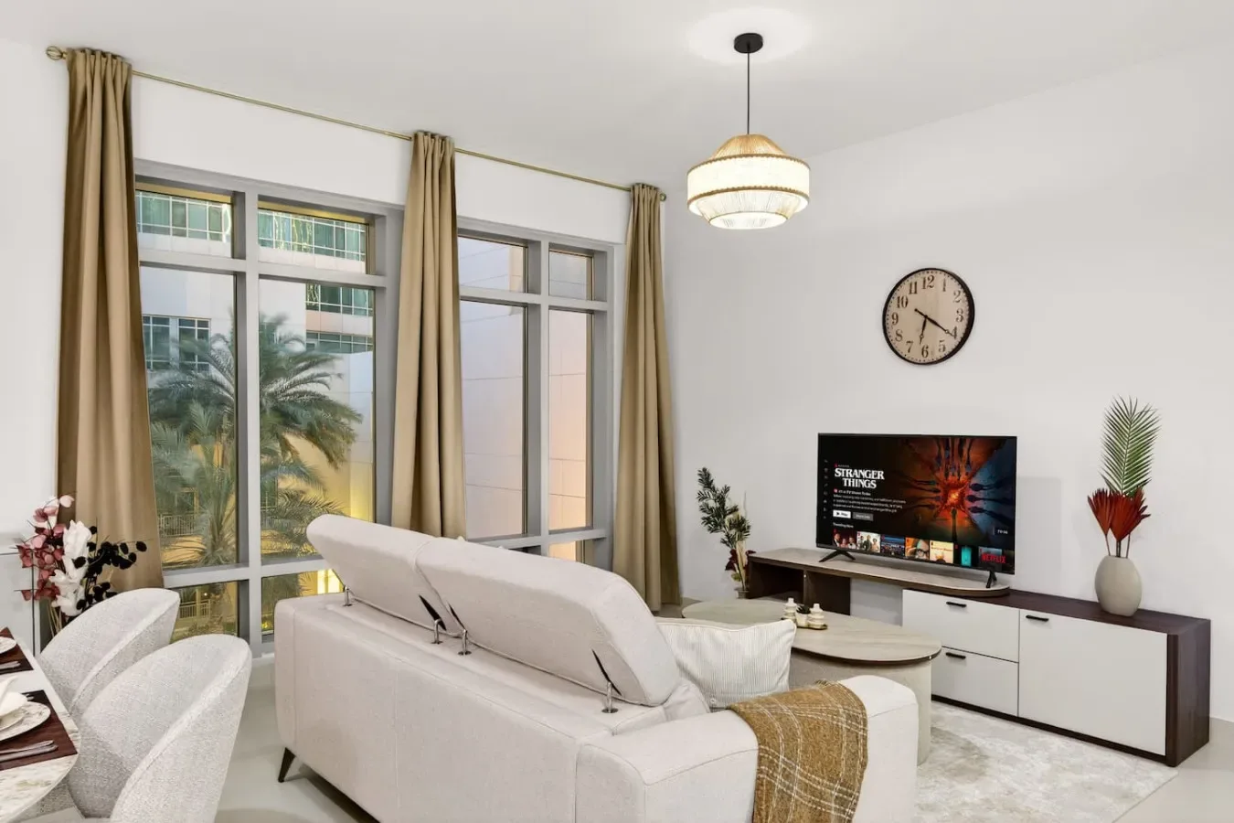 A bright living room with a sofa, television, and large windows.