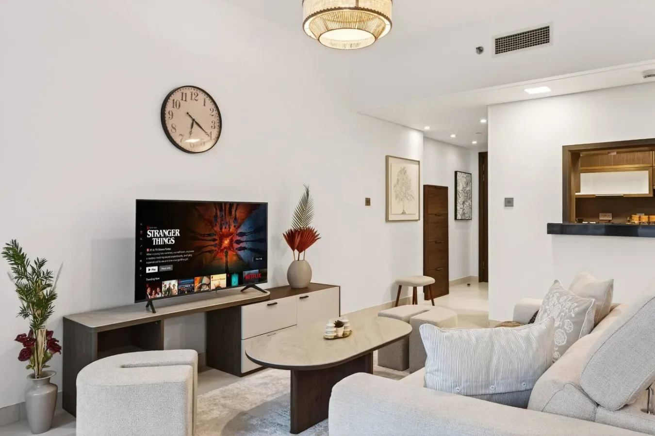 A bright living room with a television, low table, and light-colored seating.