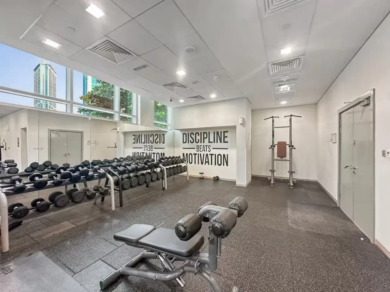 A gym weight room with dumbbells, workout benches, and exercise equipment.