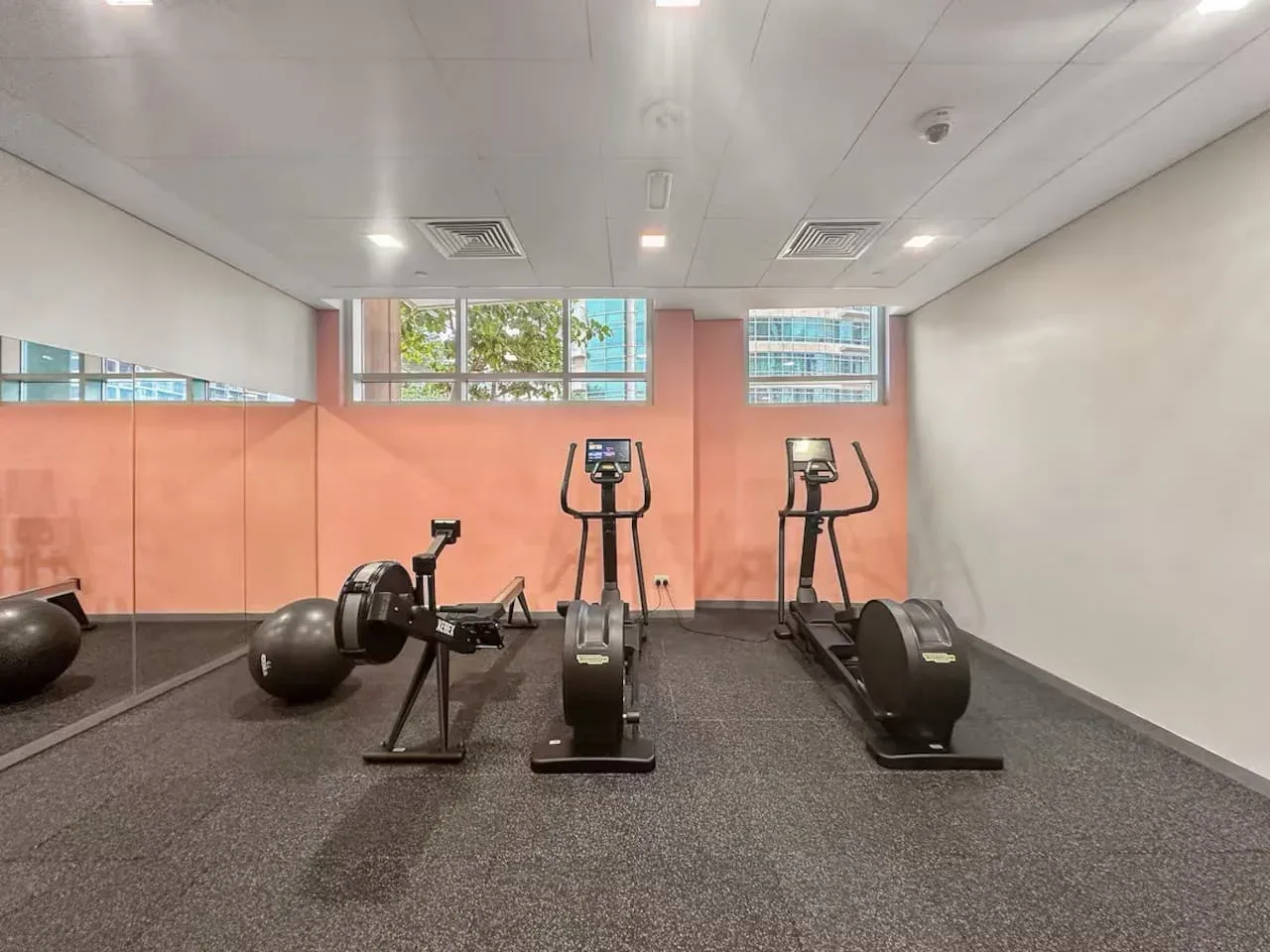 A gym with cardio machines and exercise balls on a dark floor.