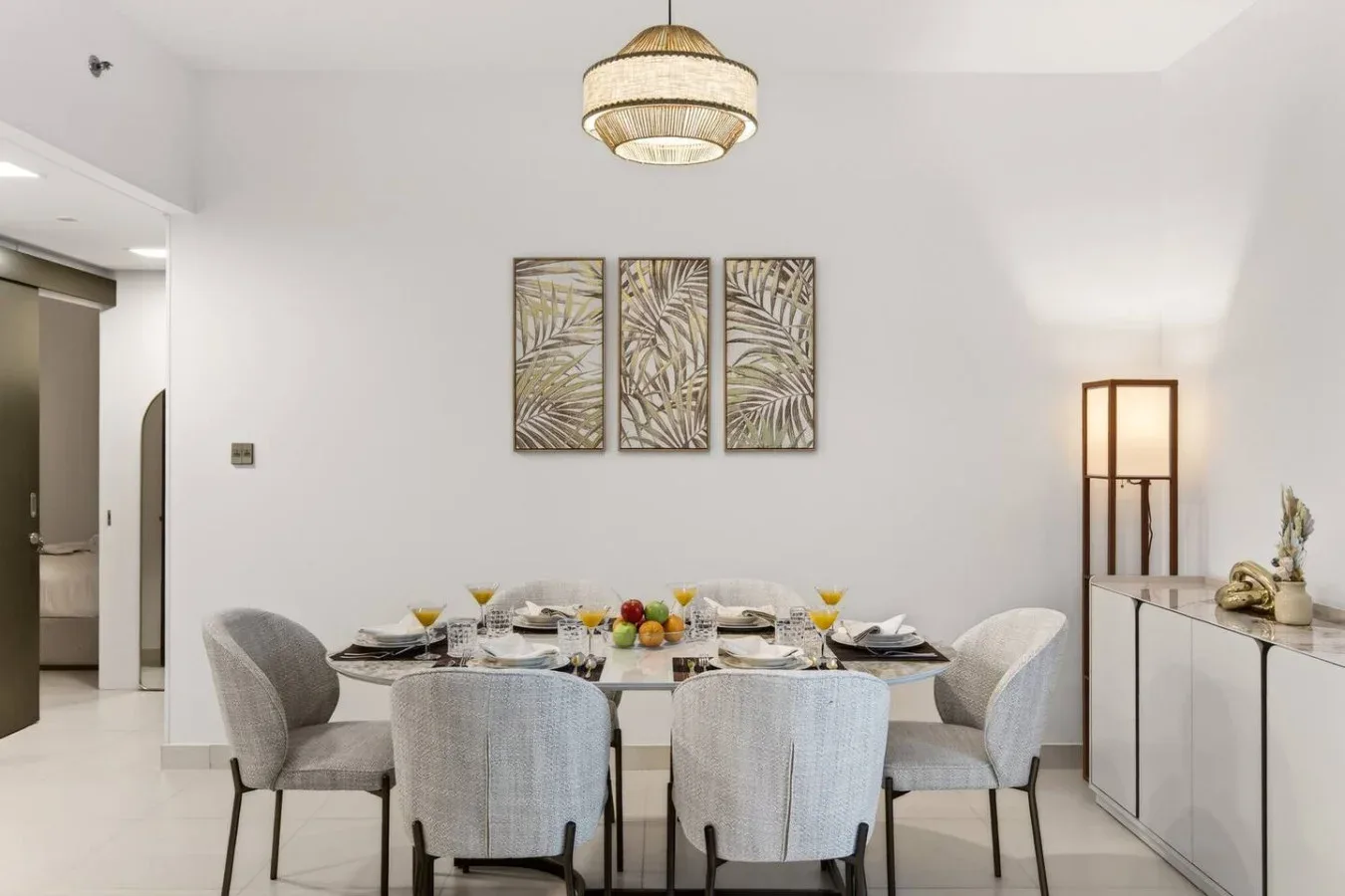 A dining area with a table set beneath a pendant light and framed wall art.