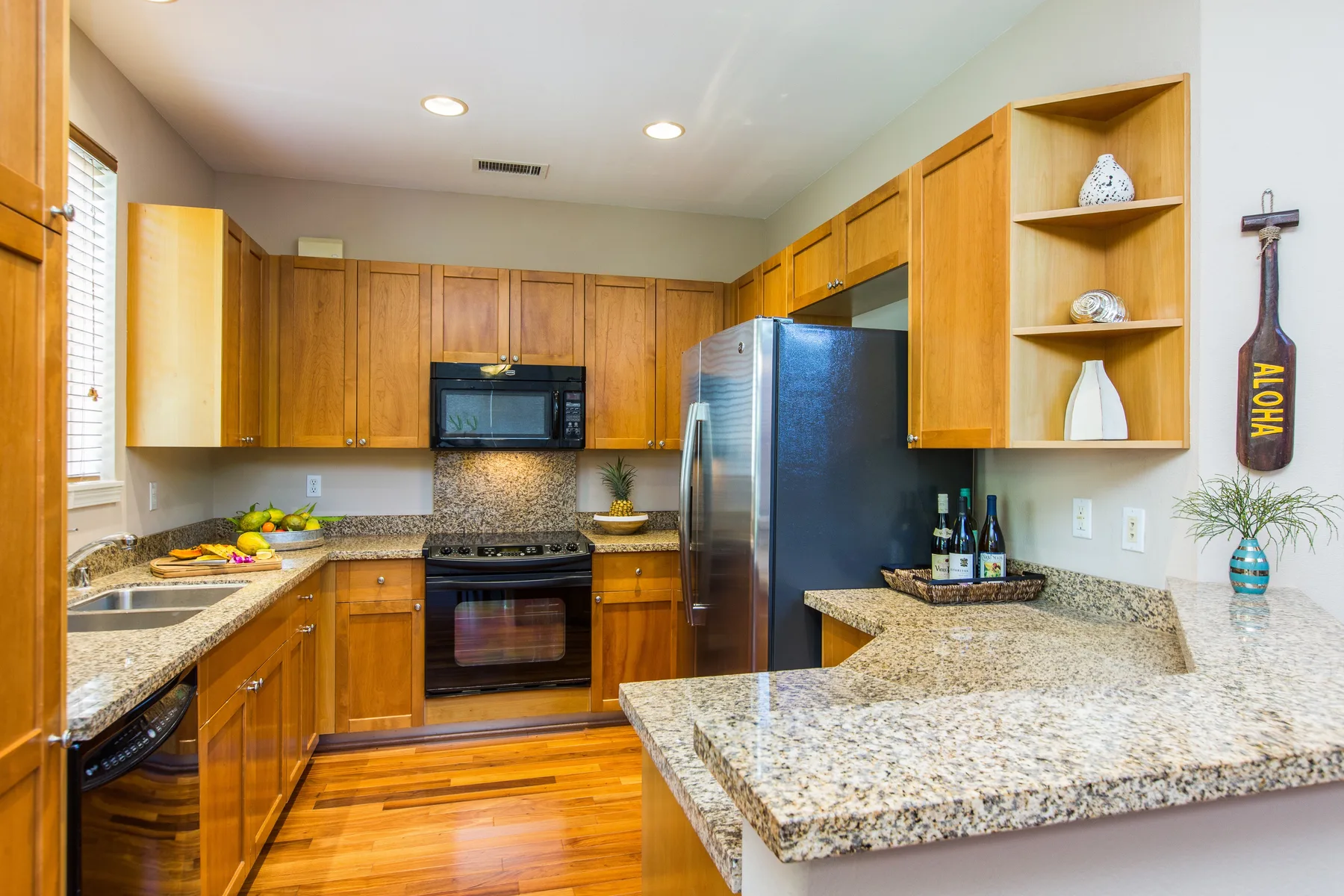 Una cocina con gabinetes de madera, electrodomésticos de acero inoxidable y encimeras de granito.