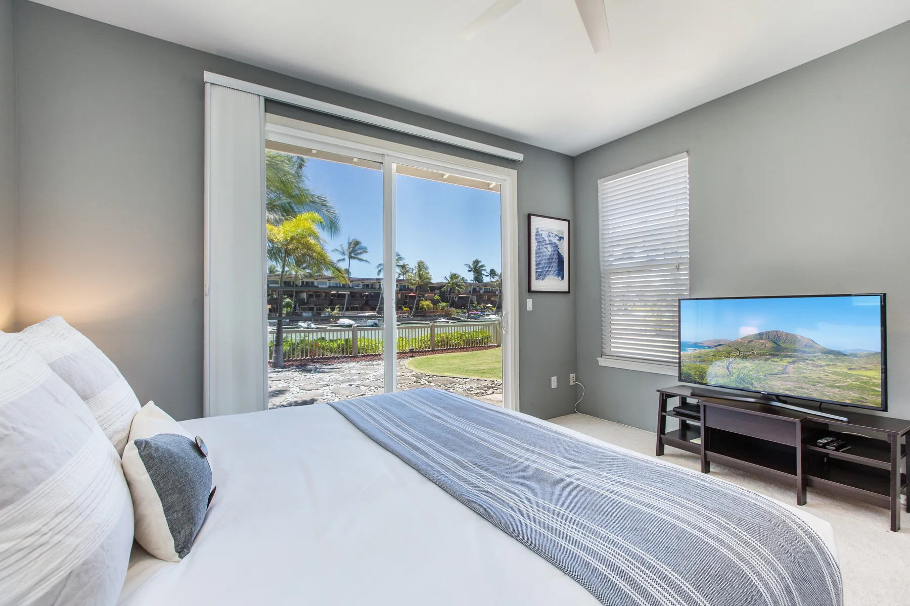 A bedroom with a large bed, sliding glass doors, and a television.