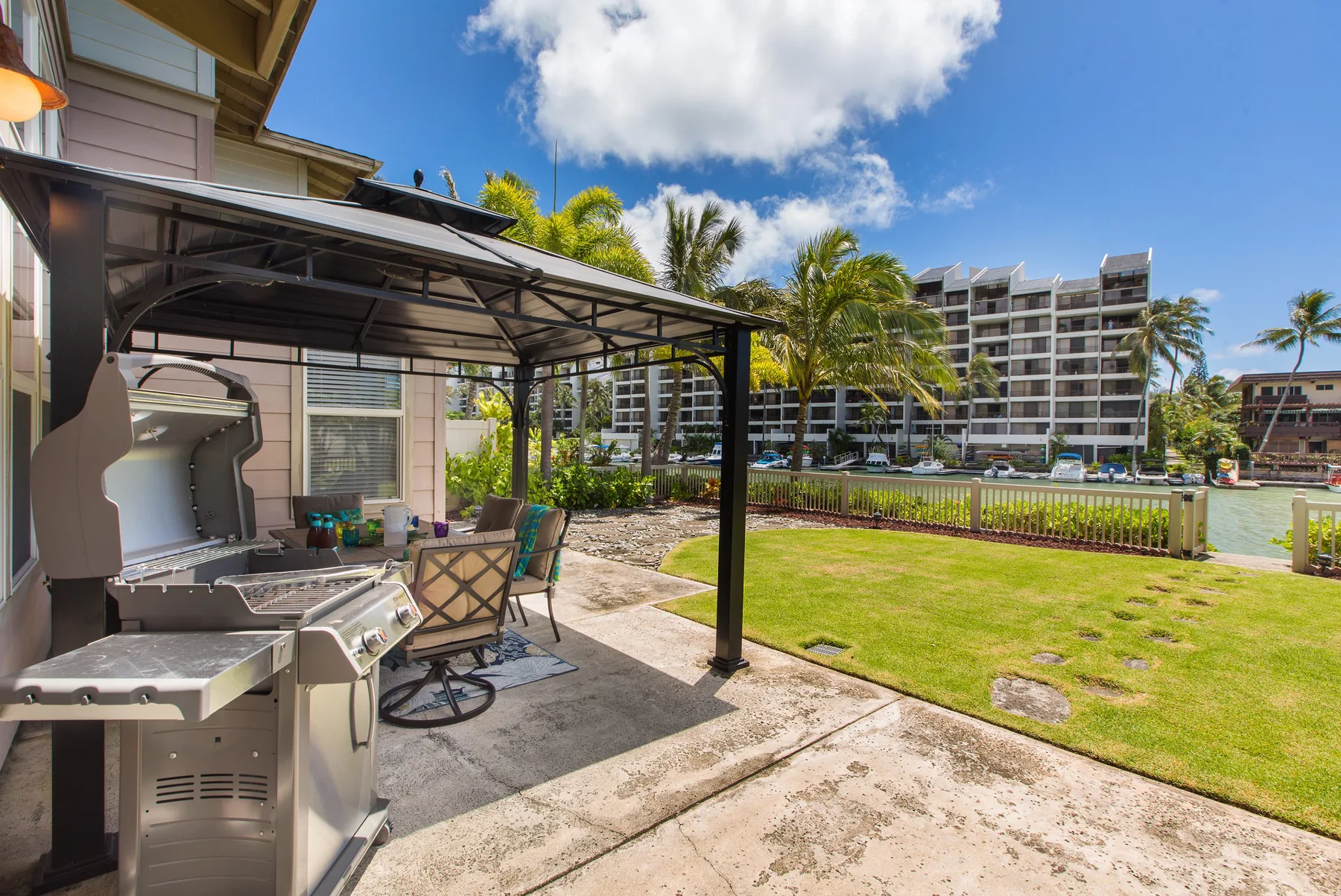 An outdoor patio with a covered seating area and a view of the lawn.
