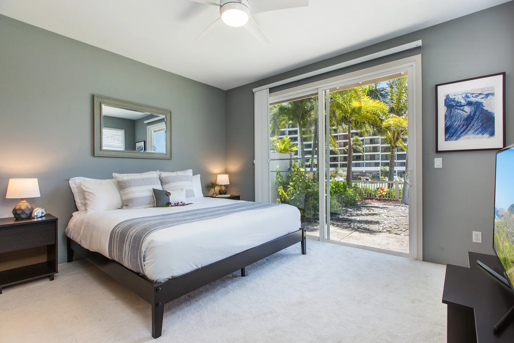 A bedroom with a bed beside sliding glass doors opening onto a patio.